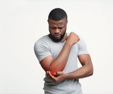 A Black man holding his elbow, which is highlighted with a red spot to show joint pain.