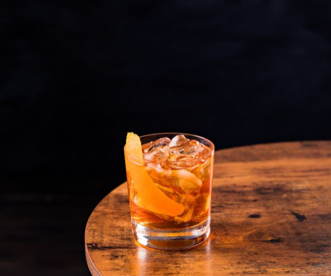 A bourbon cocktail on a wooden table.