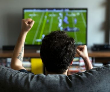 A man watching an NFL football game at home.