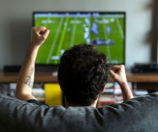A man watching an NFL football game at home.